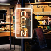 A glowing 22.8x11.8 led neon open sign in bright yellow-orange with white frame hanging from chains for business use