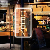 A glowing 22.8x11.8 led neon open sign in bright yellow-orange with white frame hanging from chains for business use