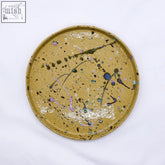 A 23 cm oliva stoneware handmade ceramic dinner plate with mustard yellow base and colorful splattered accents