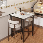 Modern white marble top bar table with sleek black metal legs and matching upholstered stools for kitchen or pub use
