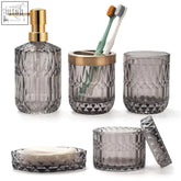 Set of five gray textured glass bathroom accessories with gold accents including soap dish and cotton swab jars