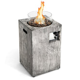 Gray wood-textured 8.79 kw propane gas pit table with glass wind guard and glowing flames over dark pebbles