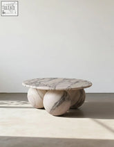 Abdurrahman round coffee table is a sleek white marble coffee table with gray veining and three rounded marble sphere legs