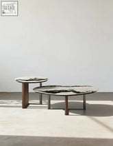 Two agatha nesting coffee tables with black and white marble tops and slender wooden legs in a minimalist style