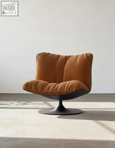 A caramel velvet swivel lounge chair with a black pedestal base perfect for a cozy relaxing spot