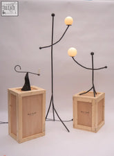 Black wrought iron table lamp with two glowing bulbs in the aluminium balancing act design