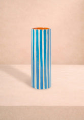A cylindrical ceramic amalfi coast vase with bold blue and white vertical stripes and a bright orange interior