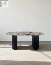 Elegant amina oval dining table with a sleek black marble top and ribbed black metal legs perfect dining table choice
