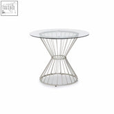 Anzio hourglass dining table with a clear glass top and silver base featuring a sleek conical wire design
