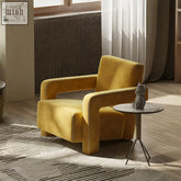 A plush mustard yellow velvet aspasia armchair with stitched detailing along the edges