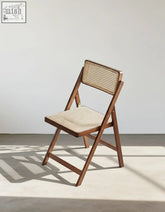 Audrey folding dining chair with a warm brown wooden frame and woven rattan backrest and seat perfect for dining