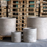 Rustic gray pigmented concrete cylinder planter with textured weathered finish for large root systems and outdoor use