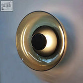 A sleek amber-tinted glass aurora wall lamp with a modern concentric circular design for stylish lighting
