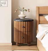 Ava luxe round bedside table with cylindrical wooden body, vertical slats, black marble top, and rounded feet