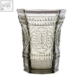 Clear glass vase with intricate embossed floral and geometric patterns paired with baroque smoked glass tumbler
