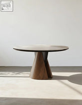Modern round dining table with dark gray marble top and walnut wood sculptural base for stylish round dining