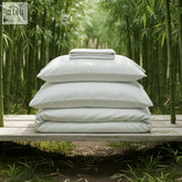 Stack of crisp white bamboo silk bed sheet set with pillows and silk duvet for a cozy sleep setup