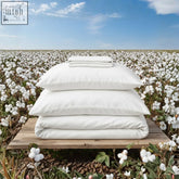 White bed sheet set with matching pillowcases made of organic cotton percale neatly stacked on wooden platform