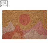 Bellevie sunrise design coir doormat with textured mountain range in pink and terracotta under orange sun on tan background