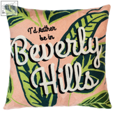 Peach-colored beverly hills needlepoint cushion with embroidered phrase and green tropical leaf patterns