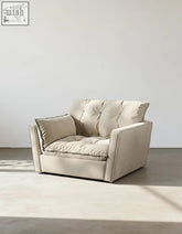 Beige tufted swivel snuggle chair with soft plush upholstery and clean-lined design for cozy seating