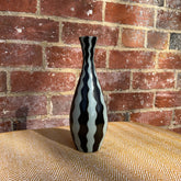 A sleek glossy ceramic studio pottery vase with bold black and white striped wavy design