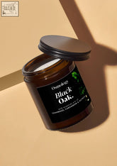 A sleek amber glass jar candle with black lid and black oak scent from osmology perfect for cozy spaces