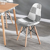 Black and white patchwork modern dining chair with wooden legs and black metal wire frame for stylish seating