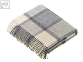 A soft folded merino lambswool throw with a windowpane block check pattern in white and grey and fringe edges