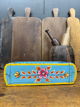 A vibrant turquoise wooden painted brick mould with yellow trim and floral designs perfect as a herb planter or storage box tray