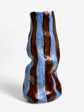 A ceramic blueberry gelato vase with a wavy form and glossy blue and brown vertical stripes