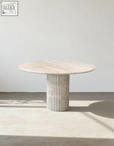 Callista round dining table with smooth light beige marble top and textured stone pedestal base perfect for dining