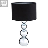 Cameo touch table lamp with black drum shade atop clear glass base featuring stacked reflective orbs and three brightness settings