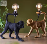 Two capuchin table lamps in matt black and gold finish with vintage bulbs held by articulated arms