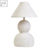 White papier mache table lamp with textured ceramic base and conical fabric shade for cozy lighting