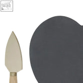 A sleek dark gray ceramic slate cheese board with rounded edges paired with a gold knife for serving