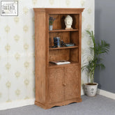 Light brown mango wood corner bookcase with intricate carvings and three shelves for living room storage and display
