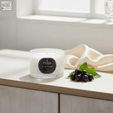 A white parks london cassis travel candle 70g in a clear glass jar with dark purple label featuring fresh green notes