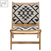 A berber style lounge chair with a light wood frame and black and white geometric patterned fabric seat and back