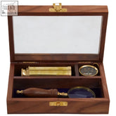 A polished wooden churchill nautical set box with brass hardware holding a brass telescope compass and magnifying glass