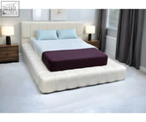 Cream-colored tufted cloud bed frame with matching headboard and dark purple mattress cover foot end view