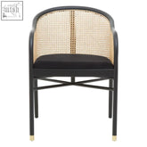 Black corso rattan chair with woven natural back and black seat cushion on slender gold-capped metal legs