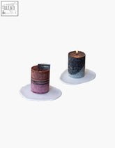 Two cosima scented candles with glittery textured surfaces in rose mauve and black silver on white ceramic coasters