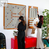 Orange-framed wall-mounted scrabble board with silver grid and colorful tiles for classic word game and vocabulary skills