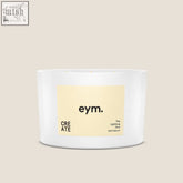 A white cylindrical three wick candle from eym with a pale yellow label called the uplifting one 100% natural