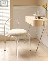 A sleek curved clear plastic dressing table chair with a plush off-white cashmere seat pad