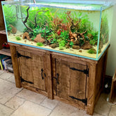 A clear glass fish tank with lush plants on a custom wooden fish tank stand showcasing natural wood finish