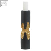 Daito large black and gold finish candle holder with matte black body and textured gold x-shaped embellishment holding a white taper candle