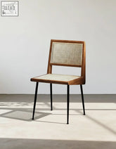 A sleek dana rattan dining chair with wooden frame, woven cane back and seat, and black metal legs perfect for dining rooms