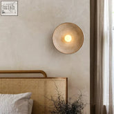 A warm white led desert wall lamp with a woven rattan finish and concentric ring design perfect for bedroom use